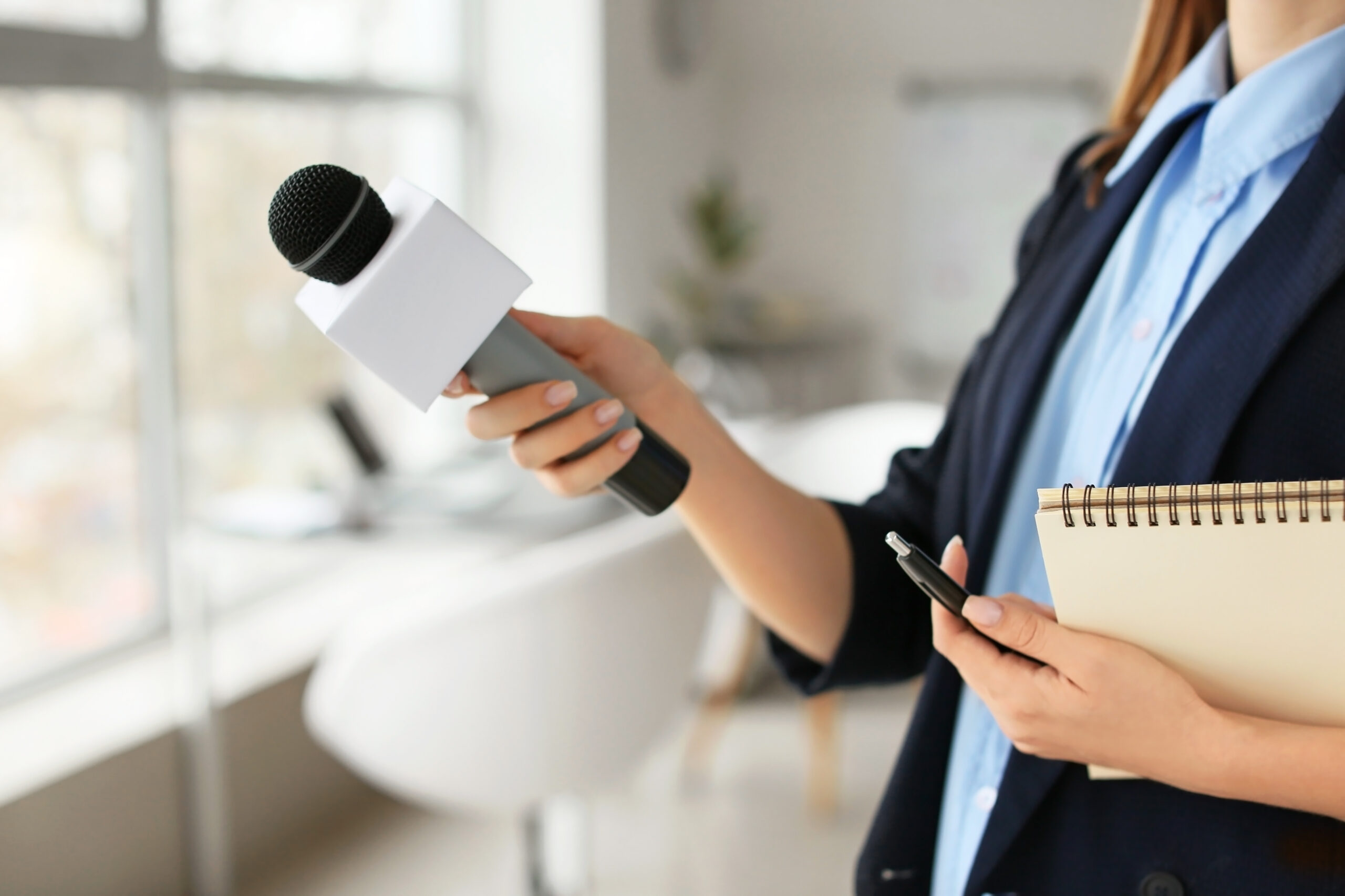 Female journalist with microphone having an interview in office